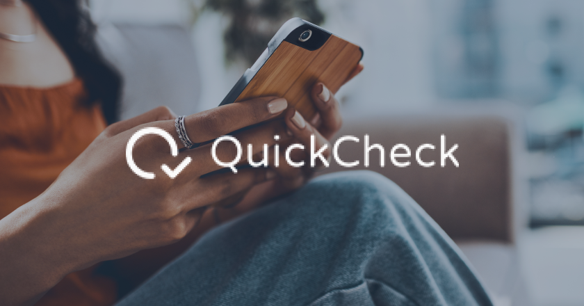 Person holding phone with QuickCheck logo overlay